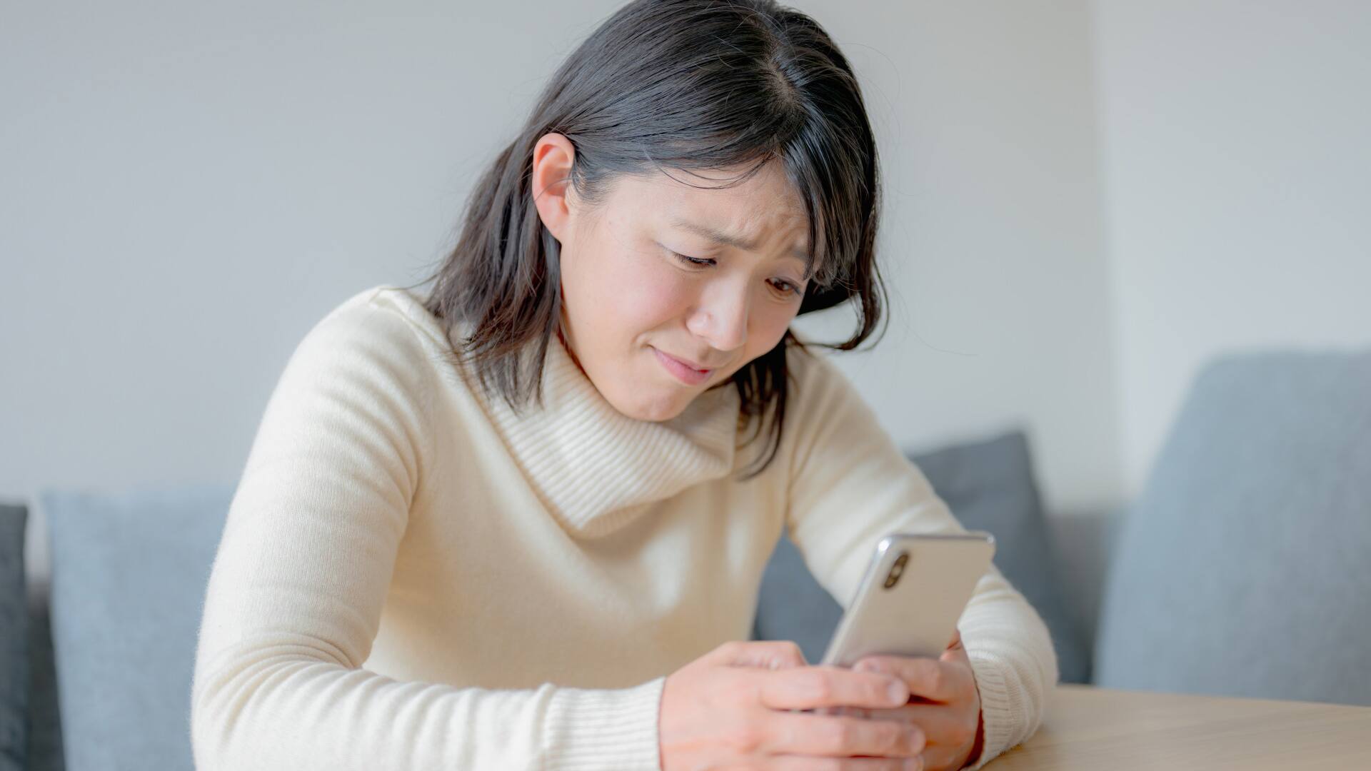 スマホを見て悩む女性