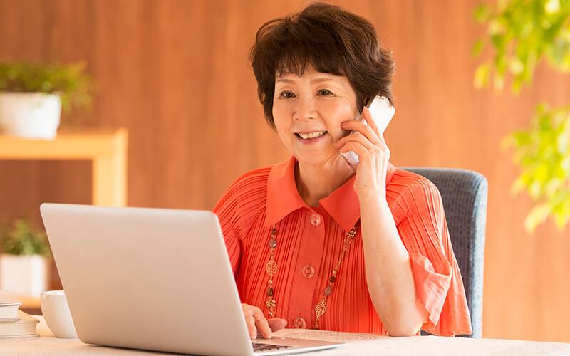 パソコンの前で携帯で話す中年女性